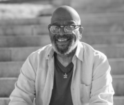 Ron Clemons, Cincinnati community activist and retired social worker, seated on outdoor steps in a black-and-white portrait photograph.