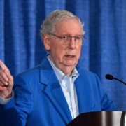 Mitch McConnell behind a podium and pointing.