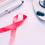 HIV_KY_2026 A red HIV awareness ribbon on a white surface beside a pen, keyboard, and stethoscope.