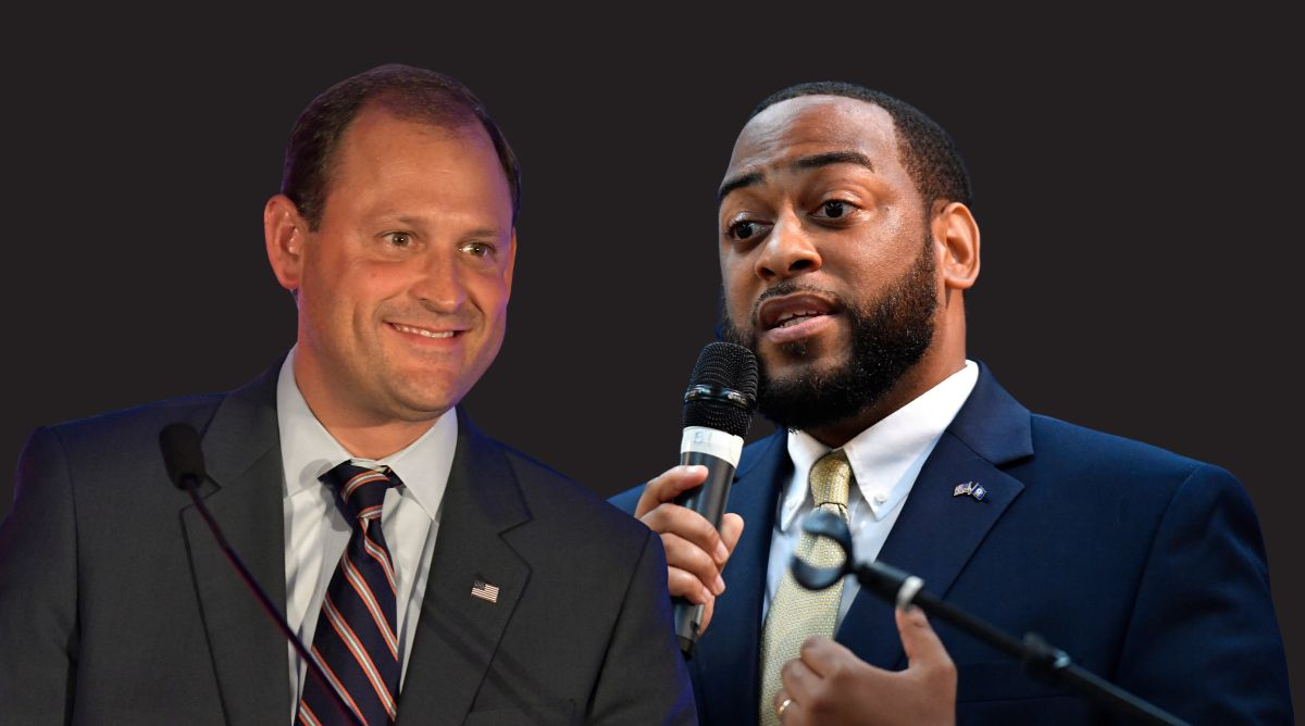 Andy Barr in a suit and striped tie smiles at a podium, beside Charles Booker speaking into a microphone, on a dark background.
